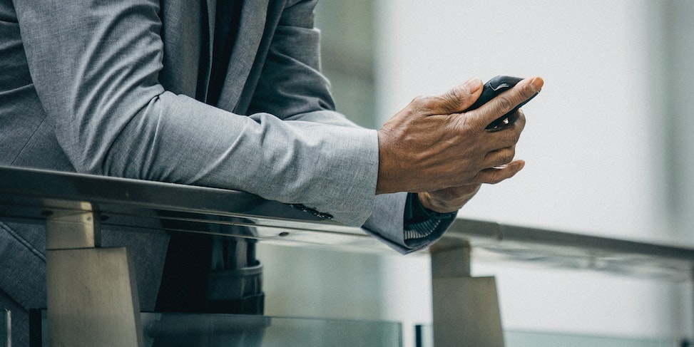 Mężczyzna w szarej marynarce korzystający z telefonu